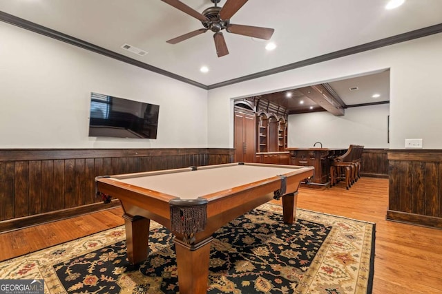 recreation room with light wood-type flooring, ceiling fan, crown molding, bar area, and pool table