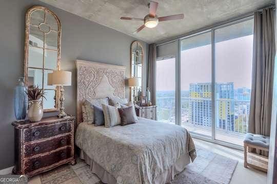 bedroom featuring access to outside, a wall of windows, and ceiling fan