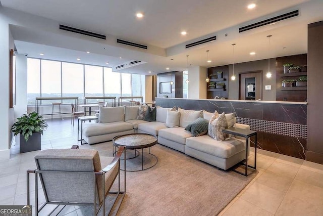 tiled living room featuring floor to ceiling windows and a water view