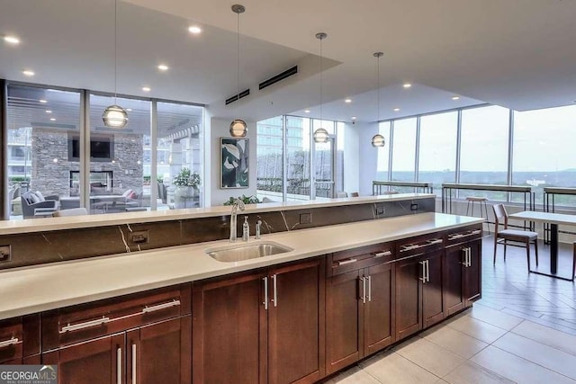 kitchen with floor to ceiling windows, a water view, hanging light fixtures, and sink