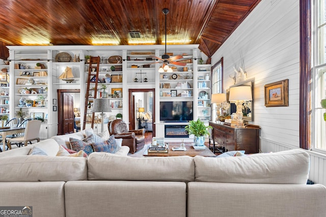 living room featuring vaulted ceiling, ceiling fan, wooden walls, and wood ceiling