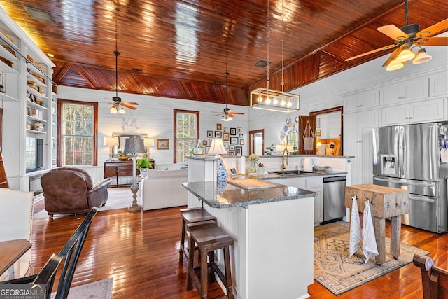 kitchen featuring white cabinetry, stainless steel appliances, kitchen peninsula, pendant lighting, and a breakfast bar