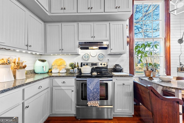 kitchen with stainless steel electric stove, white cabinets, and dark stone countertops