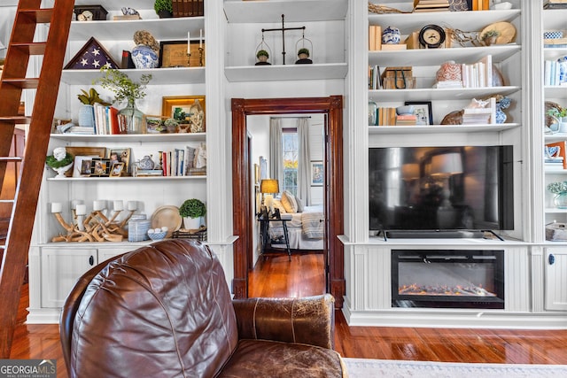 living area featuring built in shelves and dark wood-type flooring