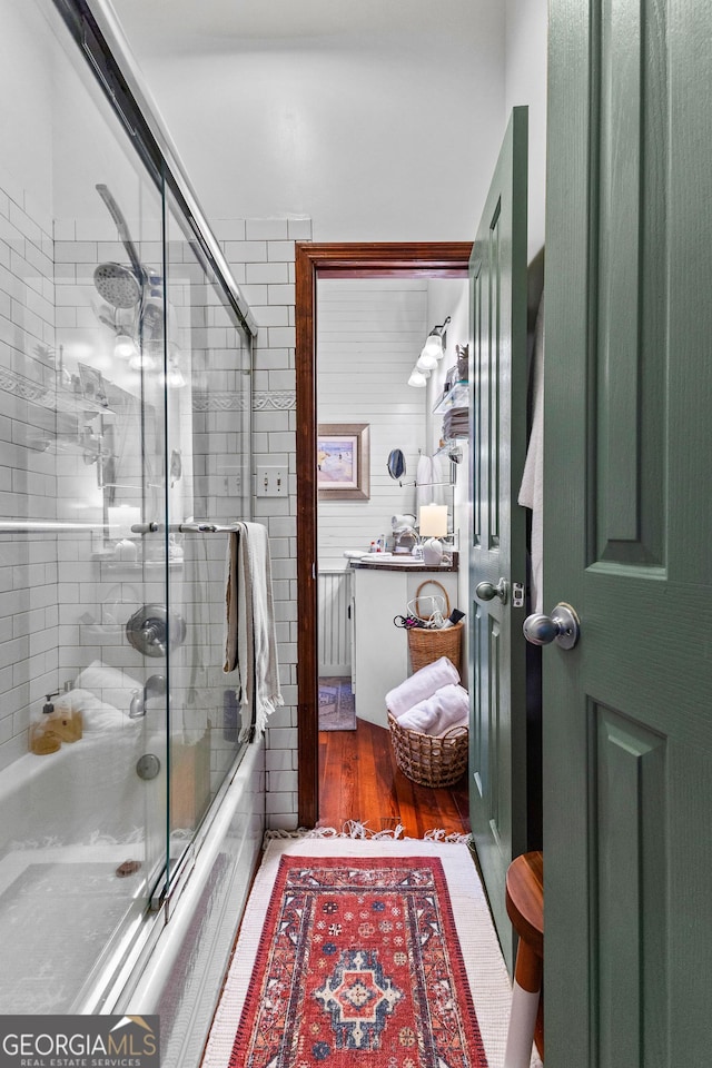 bathroom with hardwood / wood-style floors and enclosed tub / shower combo