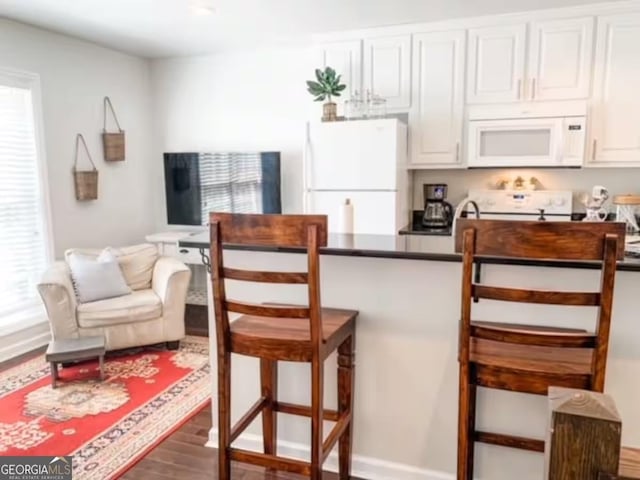 kitchen featuring hardwood / wood-style floors, white cabinetry, and white appliances