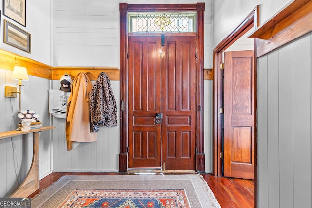 entrance foyer featuring dark hardwood / wood-style flooring and wooden walls