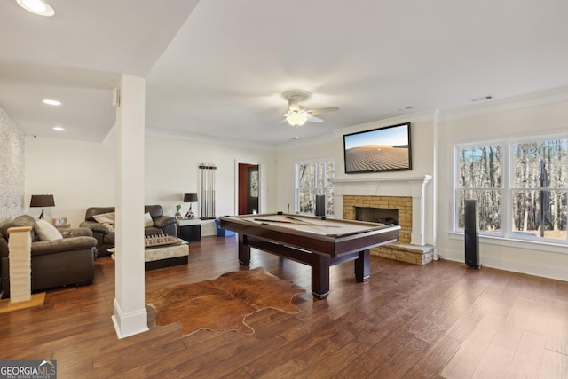 playroom with a stone fireplace, ceiling fan, ornamental molding, dark hardwood / wood-style flooring, and pool table