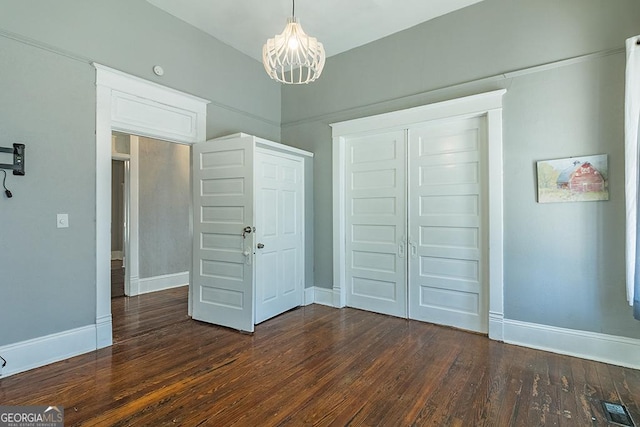 unfurnished bedroom featuring dark wood-type flooring, a closet, and a chandelier