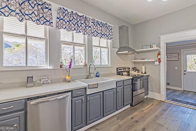 kitchen with sink, stainless steel appliances, range hood, and gray cabinets