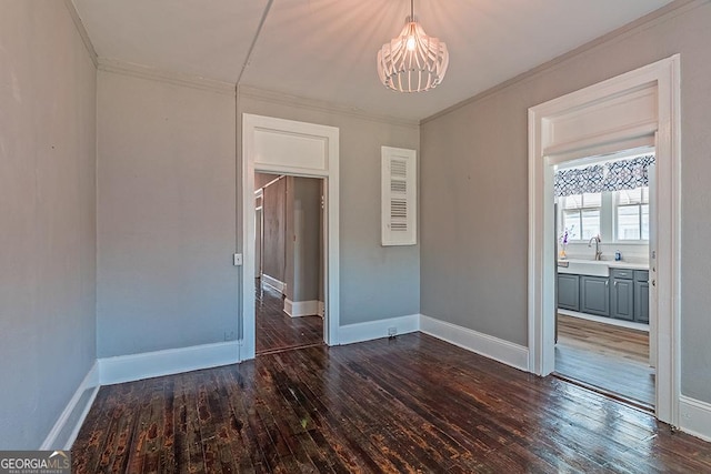 spare room featuring an inviting chandelier, crown molding, dark hardwood / wood-style flooring, and sink