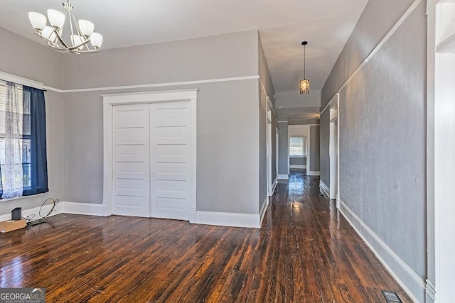 hall with dark wood-type flooring and an inviting chandelier