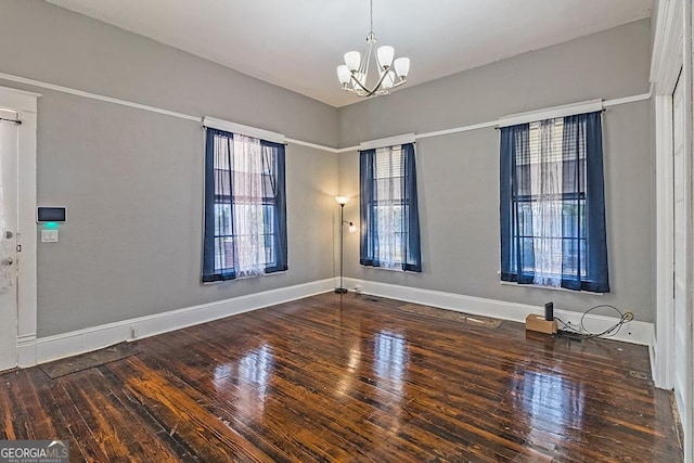 spare room featuring wood-type flooring and a notable chandelier