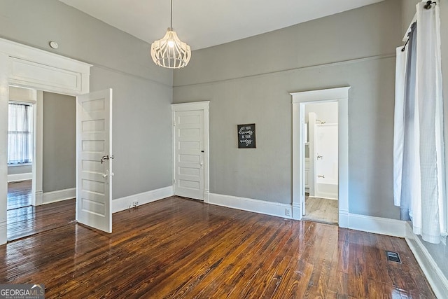 spare room with a chandelier and dark hardwood / wood-style floors