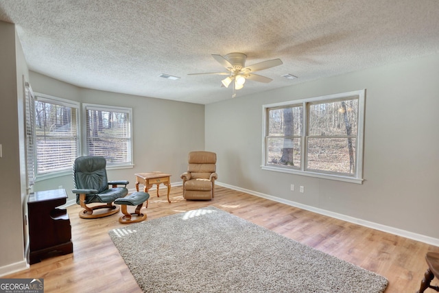 sitting room featuring ceiling fan, light wood finished floors, and baseboards