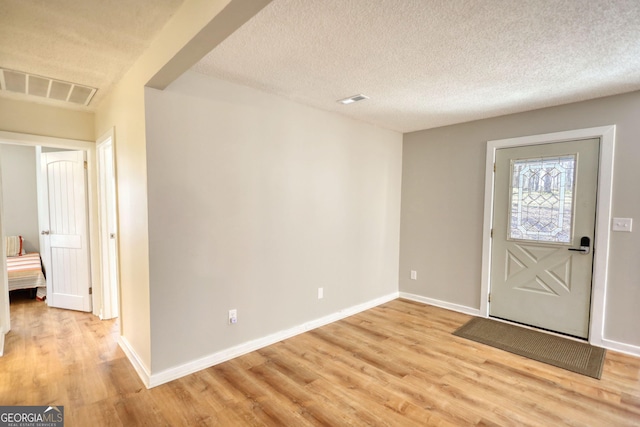 entryway with light wood-type flooring, baseboards, visible vents, and a textured ceiling