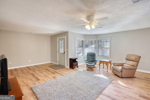 sitting room with light wood-style floors, ceiling fan, visible vents, and baseboards