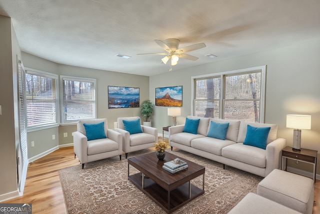 living area featuring a healthy amount of sunlight, light wood finished floors, visible vents, and baseboards