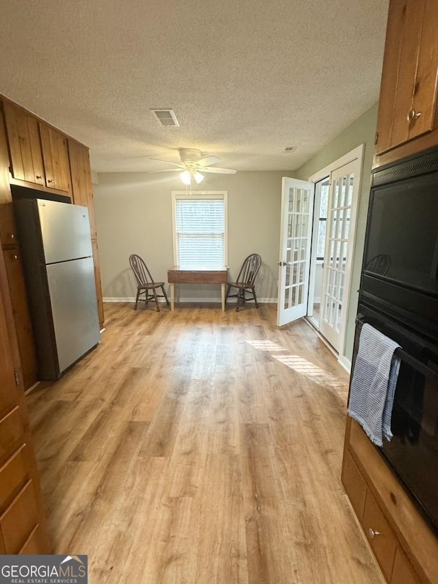 kitchen with french doors, light wood-type flooring, a textured ceiling, ceiling fan, and stainless steel refrigerator