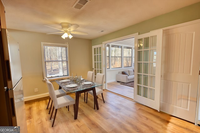 dining space with light wood-type flooring, a wealth of natural light, visible vents, and baseboards