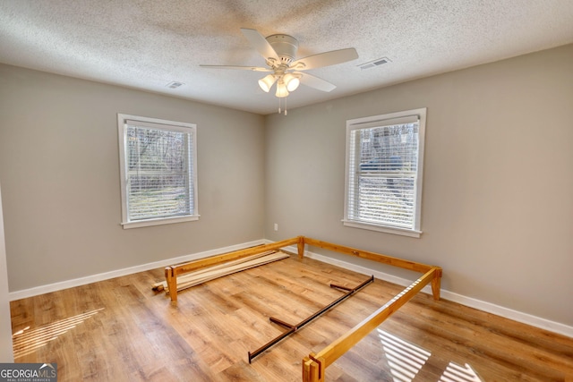 unfurnished bedroom with multiple windows, wood finished floors, and visible vents