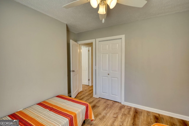 bedroom featuring light wood-style floors, ceiling fan, a textured ceiling, and baseboards