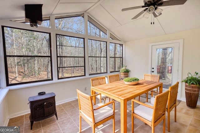 sunroom / solarium with vaulted ceiling, ceiling fan, and a wood stove