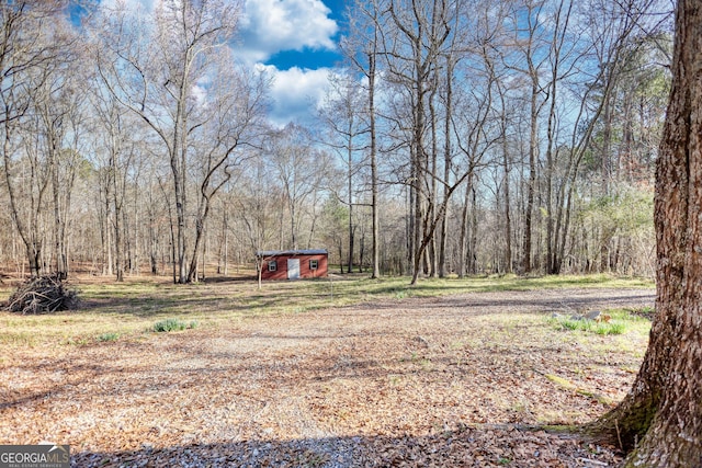 view of yard featuring an outdoor structure and a view of trees