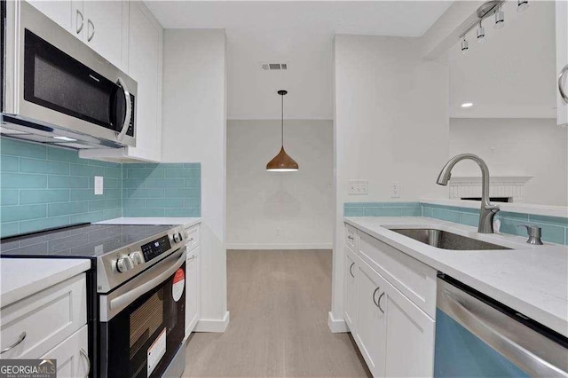 kitchen with decorative light fixtures, stainless steel appliances, white cabinetry, and sink