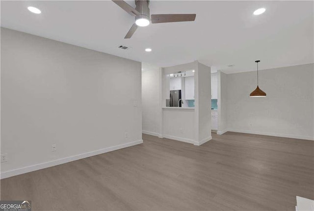 unfurnished living room featuring ceiling fan and hardwood / wood-style flooring