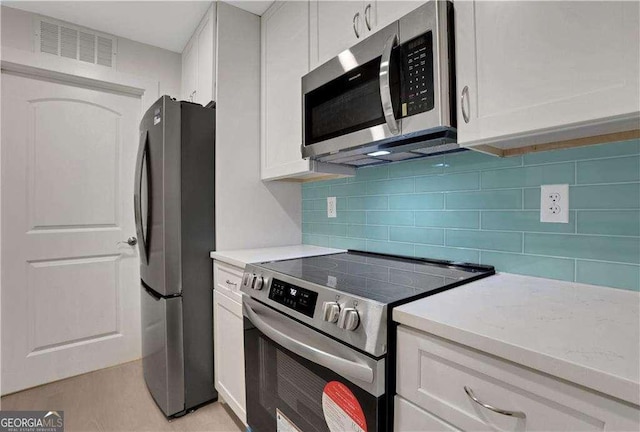 kitchen featuring white cabinets, appliances with stainless steel finishes, and backsplash