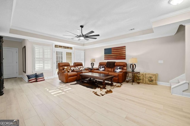 living room with a tray ceiling, light hardwood / wood-style flooring, and ornamental molding