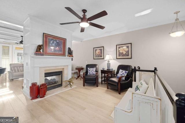 living room with ceiling fan, crown molding, a high end fireplace, and light hardwood / wood-style flooring