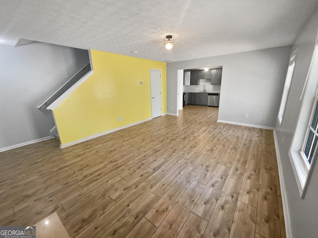 unfurnished living room with a textured ceiling, hardwood / wood-style flooring, and sink