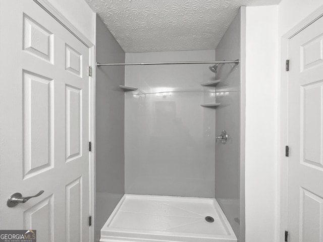 bathroom with a textured ceiling and walk in shower