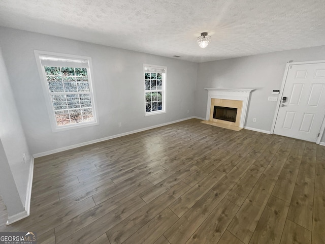 unfurnished living room with dark hardwood / wood-style flooring and a textured ceiling