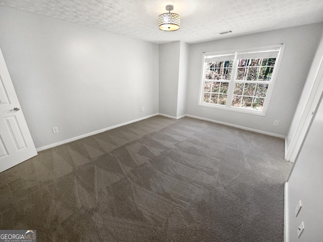 unfurnished room featuring dark colored carpet and a textured ceiling