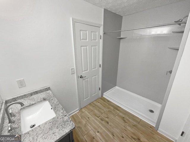 bathroom featuring a textured ceiling, vanity, and walk in shower