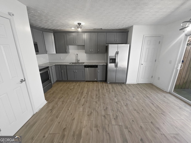 kitchen with decorative backsplash, appliances with stainless steel finishes, gray cabinetry, and sink