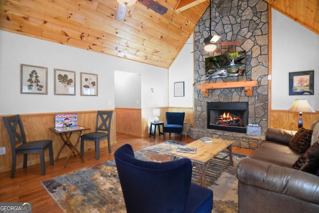 living room with ceiling fan, wood-type flooring, high vaulted ceiling, wooden ceiling, and a fireplace