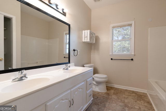 bathroom featuring double vanity, a sink, toilet, and baseboards