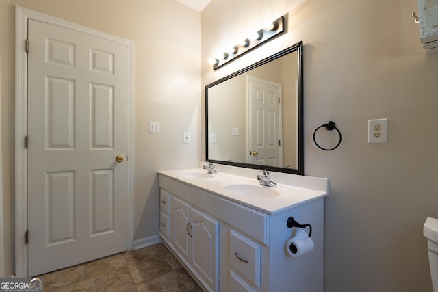 bathroom with a sink, toilet, and double vanity