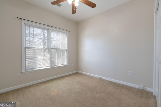 spare room with a ceiling fan, light carpet, visible vents, and baseboards