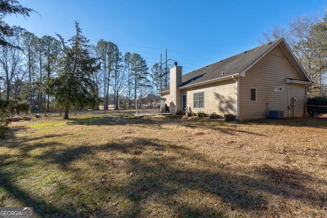 view of property exterior with a chimney, central AC, and a yard