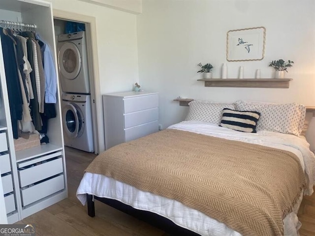 bedroom featuring stacked washer / drying machine, a closet, and dark hardwood / wood-style flooring