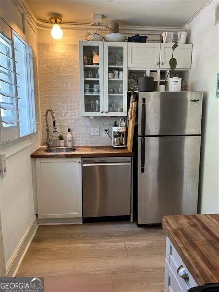 kitchen with sink, white cabinets, stainless steel appliances, and wooden counters