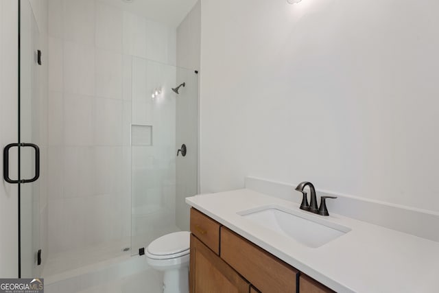 bathroom with vanity, a shower with door, and toilet