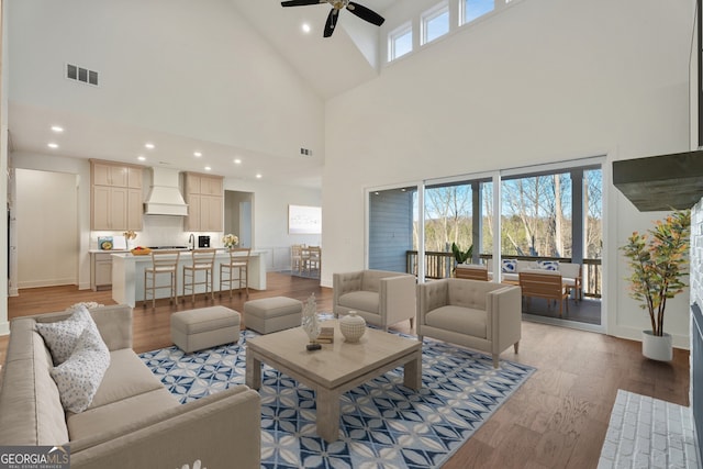 living room featuring light hardwood / wood-style flooring, ceiling fan, and a high ceiling