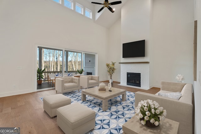 living room featuring ceiling fan, a towering ceiling, and hardwood / wood-style floors