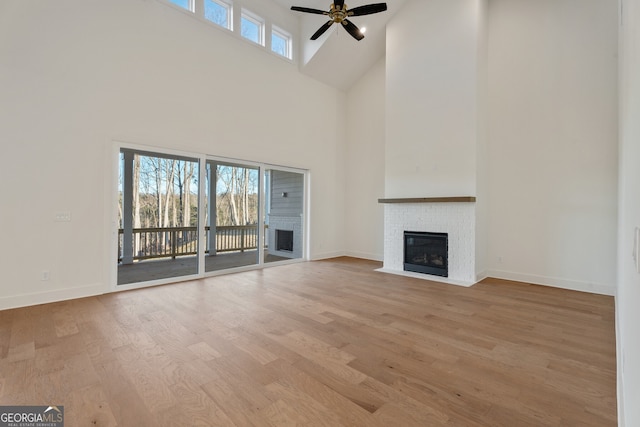 unfurnished living room with a towering ceiling, light hardwood / wood-style floors, and ceiling fan